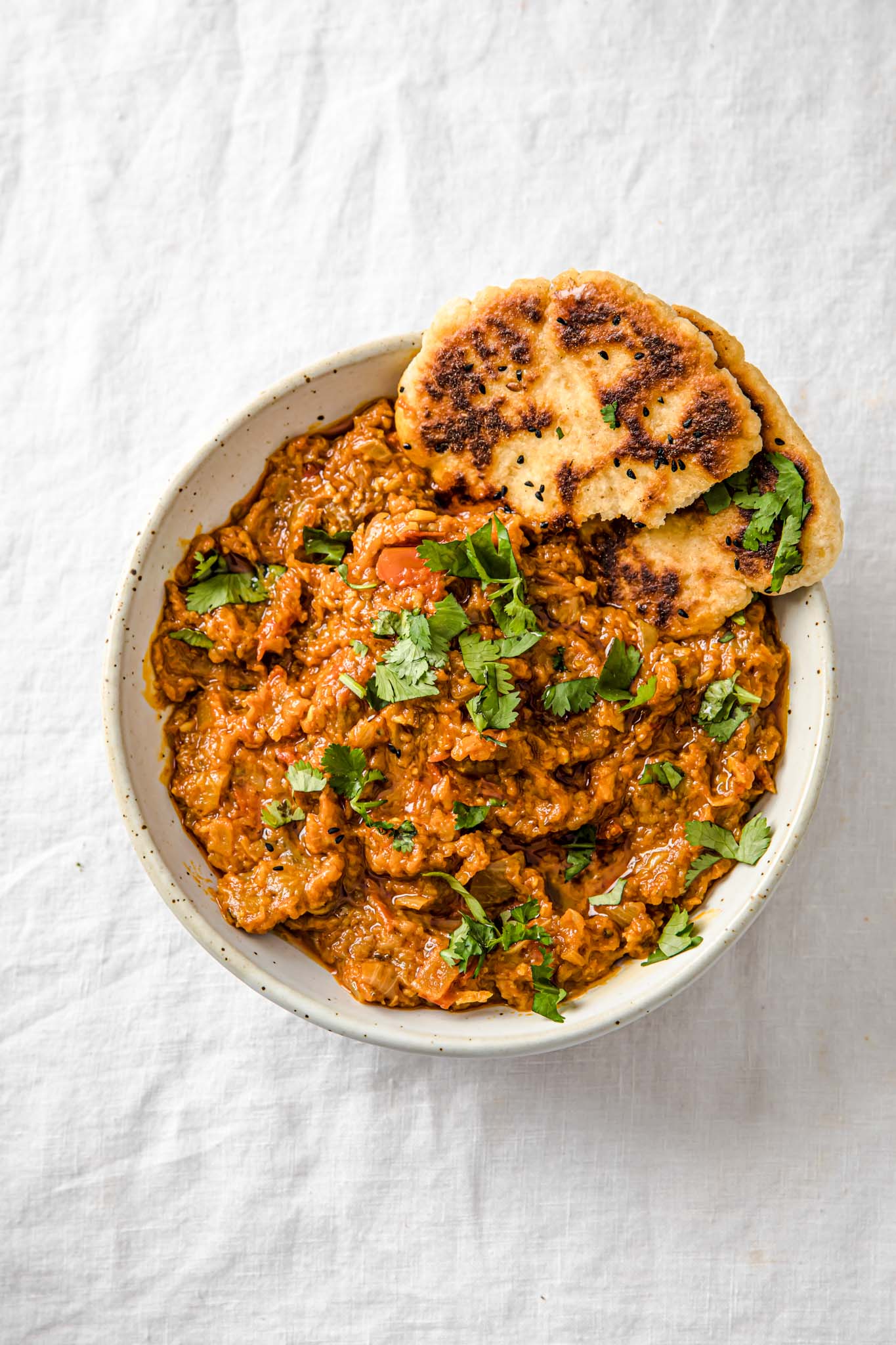 Delicious roasted mashed eggplant garnished with fresh herbs in a white bowl.