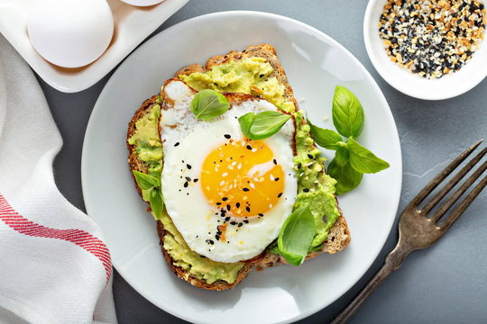 Healthy avocado toast with a fried egg and mustard on whole grain bread. Perfect for a nutritious br.