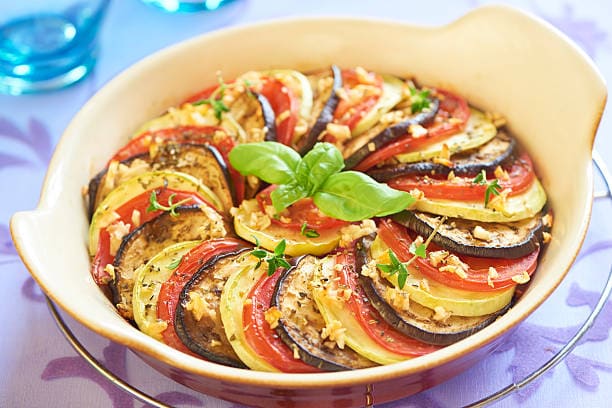 Colorful vegetable tian with layered zucchini, eggplant, and tomatoes.
