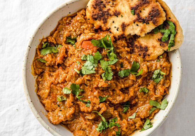 Delicious roasted mashed eggplant garnished with fresh herbs in a white bowl.