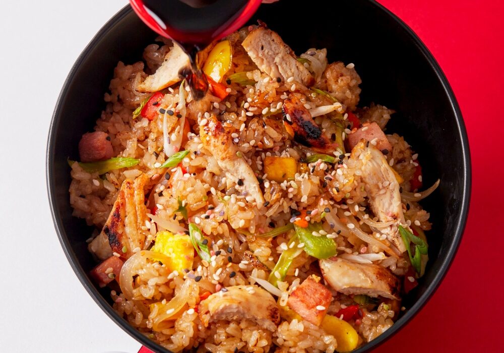 Healthy chicken and cauliflower rice bowl with colorful vegetables and sesame seeds.