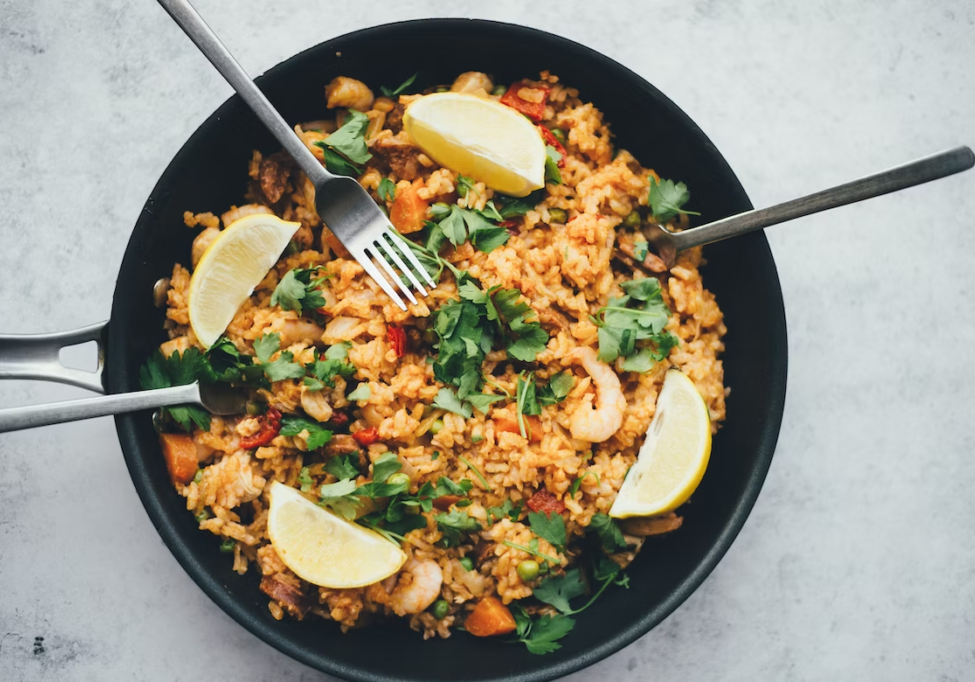 Delicious cauliflower fried rice garnished with lemon wedges and fresh herbs.