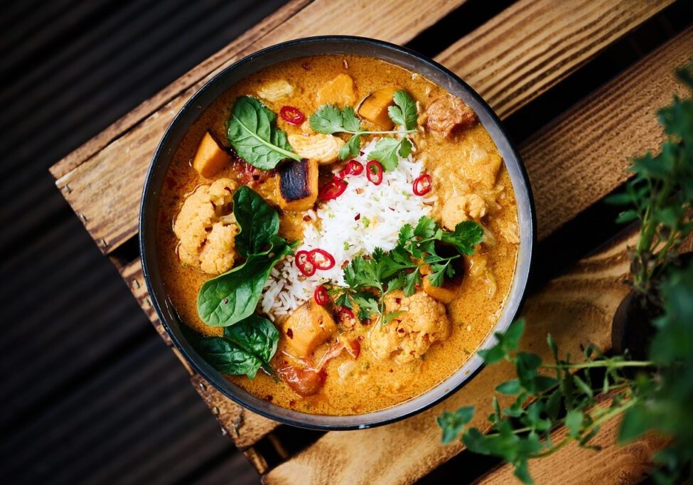Vibrant Indian vegetable stew with fresh herbs, spices, and coconut milk, served in a black bowl for.