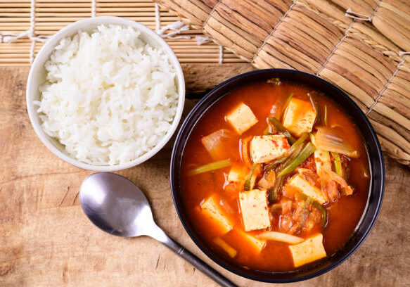 Korean food, Kimchi soup with fofu eating with cooked rice on wooden background, Top view