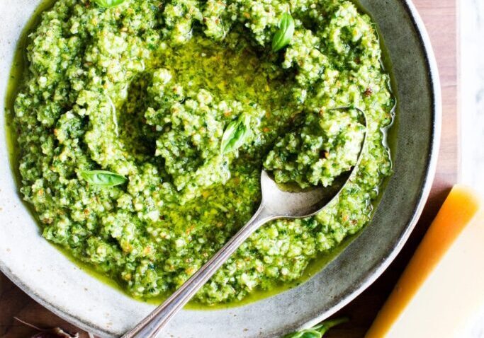 Arugula walnut pesto in a bowl with a spoon, fresh and vibrant green.