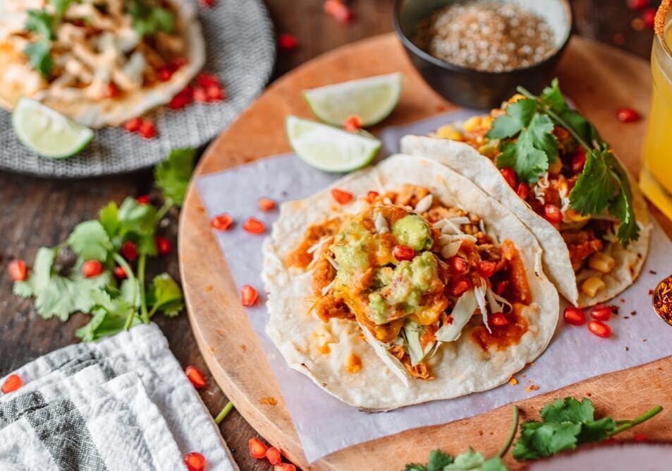 Vegetarian lentil tacos with fresh vegetables and guacamole on a wooden serving board.