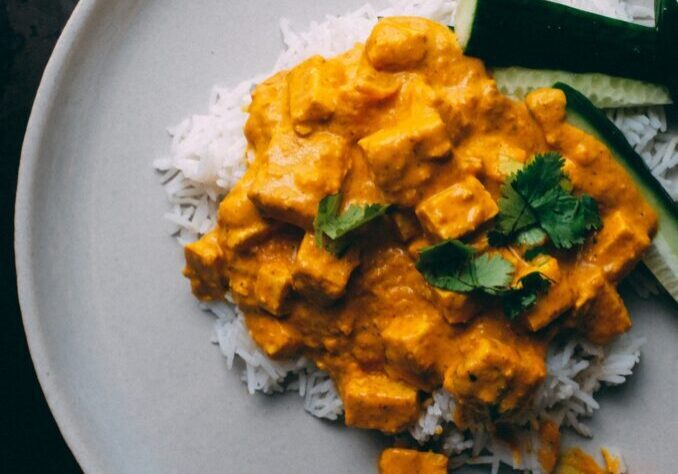 Vegan Indian curry with tofu served over white rice and fresh cucumber slices.