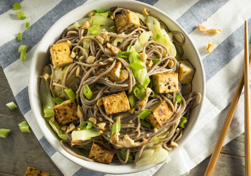 Healthy Asian-inspired noodle bowl with tofu, cabbage, and green onions.