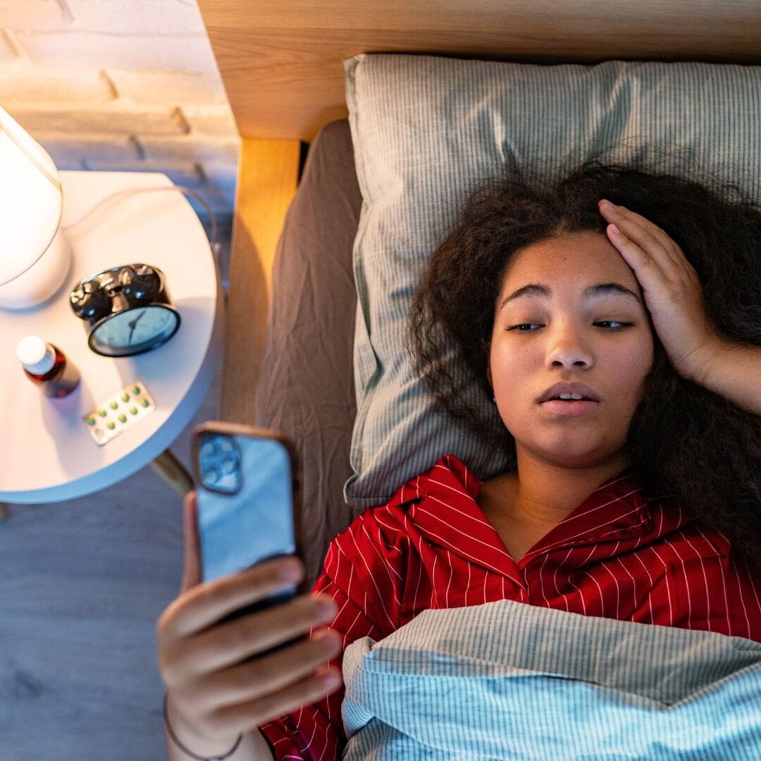 Poor sleep woman in bed checking her phone